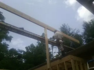 Carpenter setting a ridge beam over a new addition frame — Ice Dam Removal by Roofing Brothers in Monclova