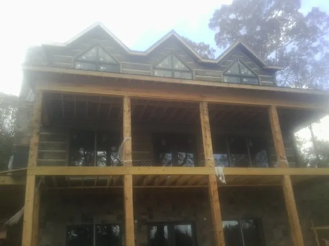 Dormers and porch framing on a large log home under construction — Roof Coating work by our crew in Monclova