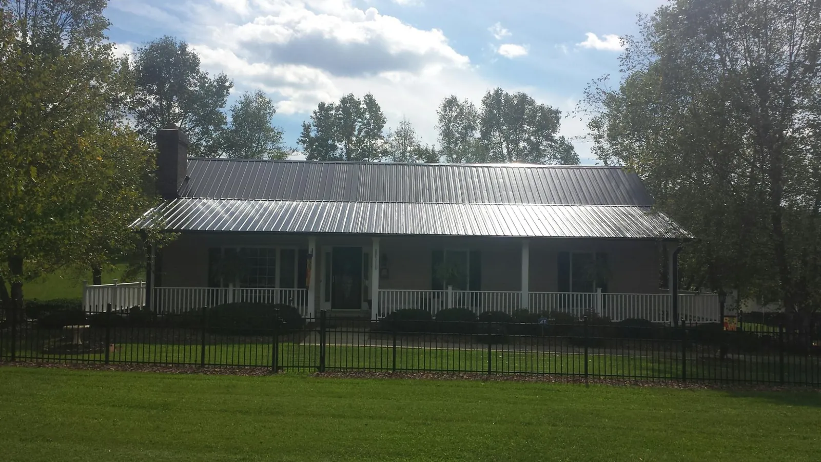 Gray metal roof on a brick ranch with a full width front porch — Gutter Guard Installation work by our crew in Monclova