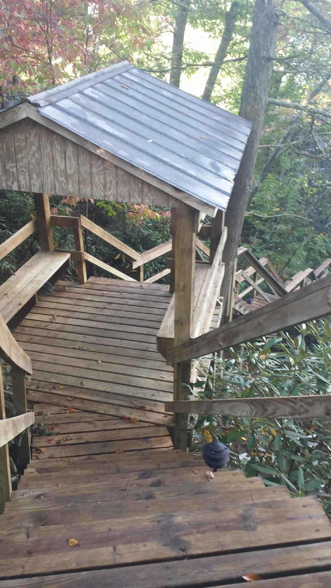 Metal roofed shelter over wooden steps on a wooded walkway — Skylight Repair & Installation work by our crew in Monclova
